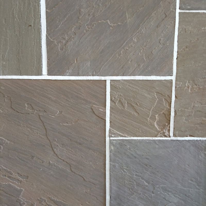 A close-up shows Strata 22mm Calibrated Sandstone Autumn tiles in gray and beige, featuring strata-like textured surfaces with visible lines and color variations. The neatly arranged tiles are separated by white grout.