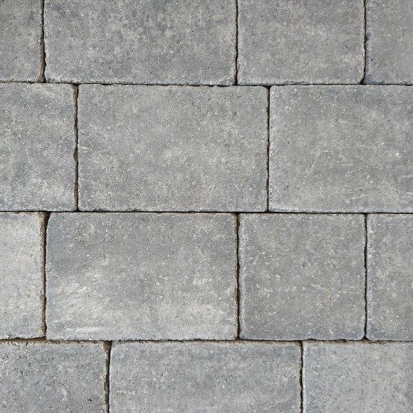 A close-up of the Barleystone Kingspave Cobble Silver Grey shows a textured brick wall with a rectangular pattern. The slightly rough surfaces and subtle color variations create a uniform yet rustic appearance reminiscent of its stunning silver-grey shade.