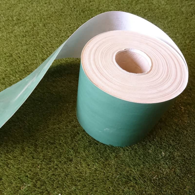 A roll of Joining Tape is partially unrolled on a grassy surface, with its shiny adhesive underside glistening as it spirals away, ideal for seamless joining on any project.