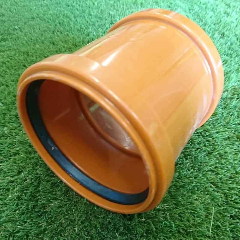 A 110mm Double Socket Collar, featuring an orange exterior, black interior lining, and a double socket design, is positioned on green artificial grass.