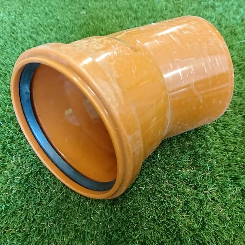 A 110mm orange 30° single socket bend with a rubber gasket rests on green artificial grass, facilitating easy connections.