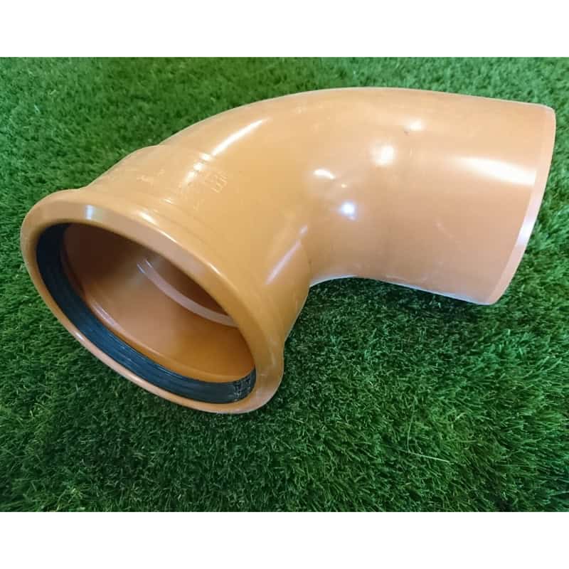 The 110mm 90° Single Socket Bend, featuring an orange PVC and rubber seal, is shown on a grass-like surface. Ideal for plumbing or drainage systems.