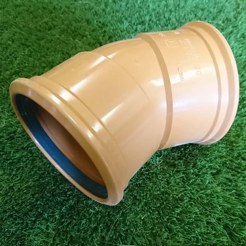 A 110mm tan PVC 30° Double Socket Bend with a visible rubber gasket and ridges lies on grass.