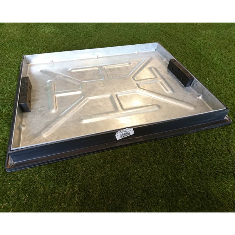 A metal 600x450mm Screed Cover & Frame, with a rectangular shape and raised edges, rests on grass. It has geometric patterns, two clips on one side, and a small white label underneath.