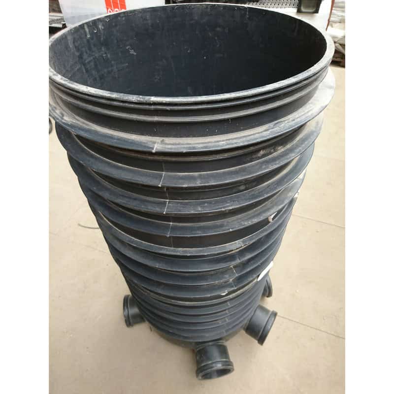 A tall, cylindrical black plastic 460mm Base & Riser with multiple openings stands upright on a concrete floor in a workshop or hardware store setting.