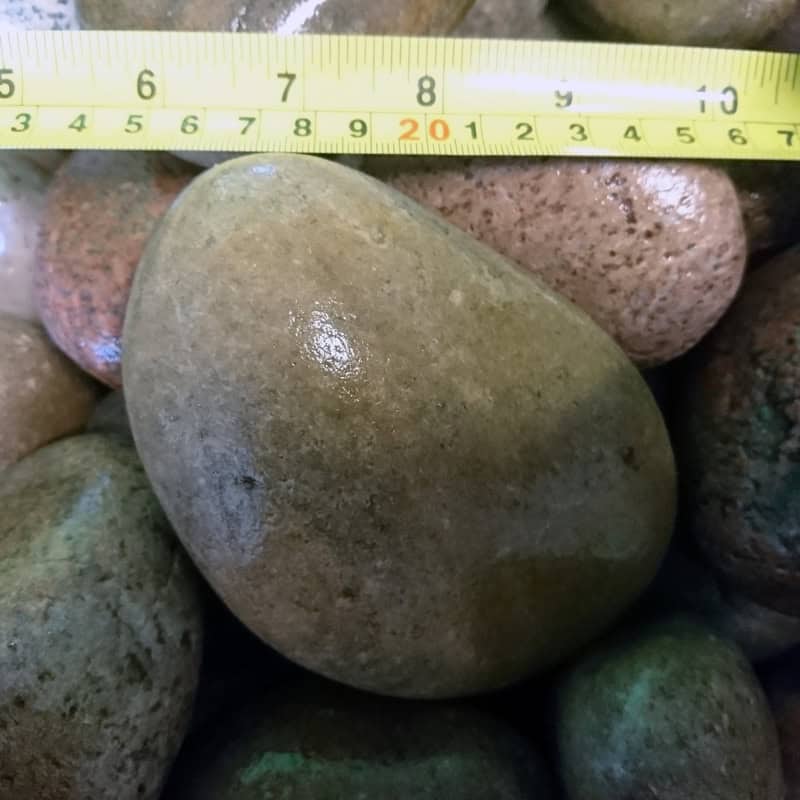 A close-up features Scottish Highland Pebbles, 80-120mm, in various browns and grays. The largest pebble measures about 20 cm with a measuring tape above it. These pebbles come bagged.