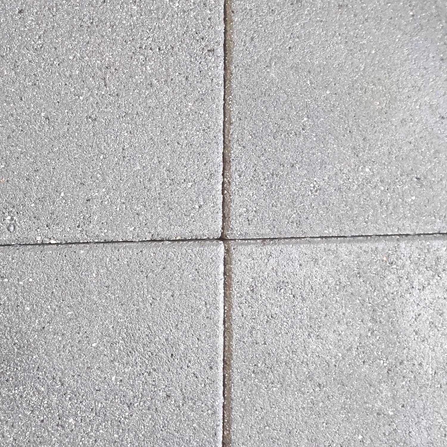 Close-up of four Barleystone Granite Paving Slabs Natural forming a grid. The textured surface has visible specks, and the slabs align with slightly recessed grout lines for a symmetrical pattern. The dominant color is neutral gray.