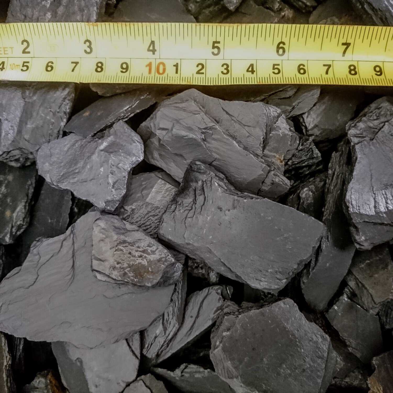 Close-up of Slate Grey 40mm - Loose rocks with a yellow metric measuring tape above, showing their size.