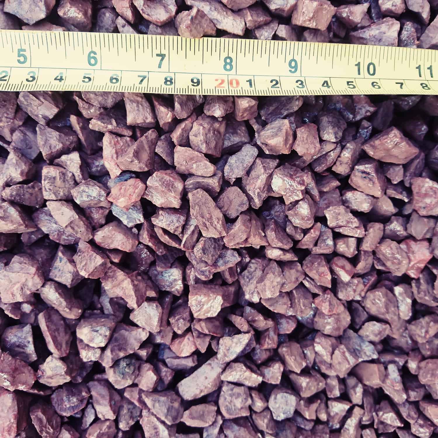 A close-up image shows small, rough stones identified as Red Granite 14mm-Loose. A measuring tape runs across the reddish-brown stones, displaying measurements in centimeters, with 20 prominently centered.