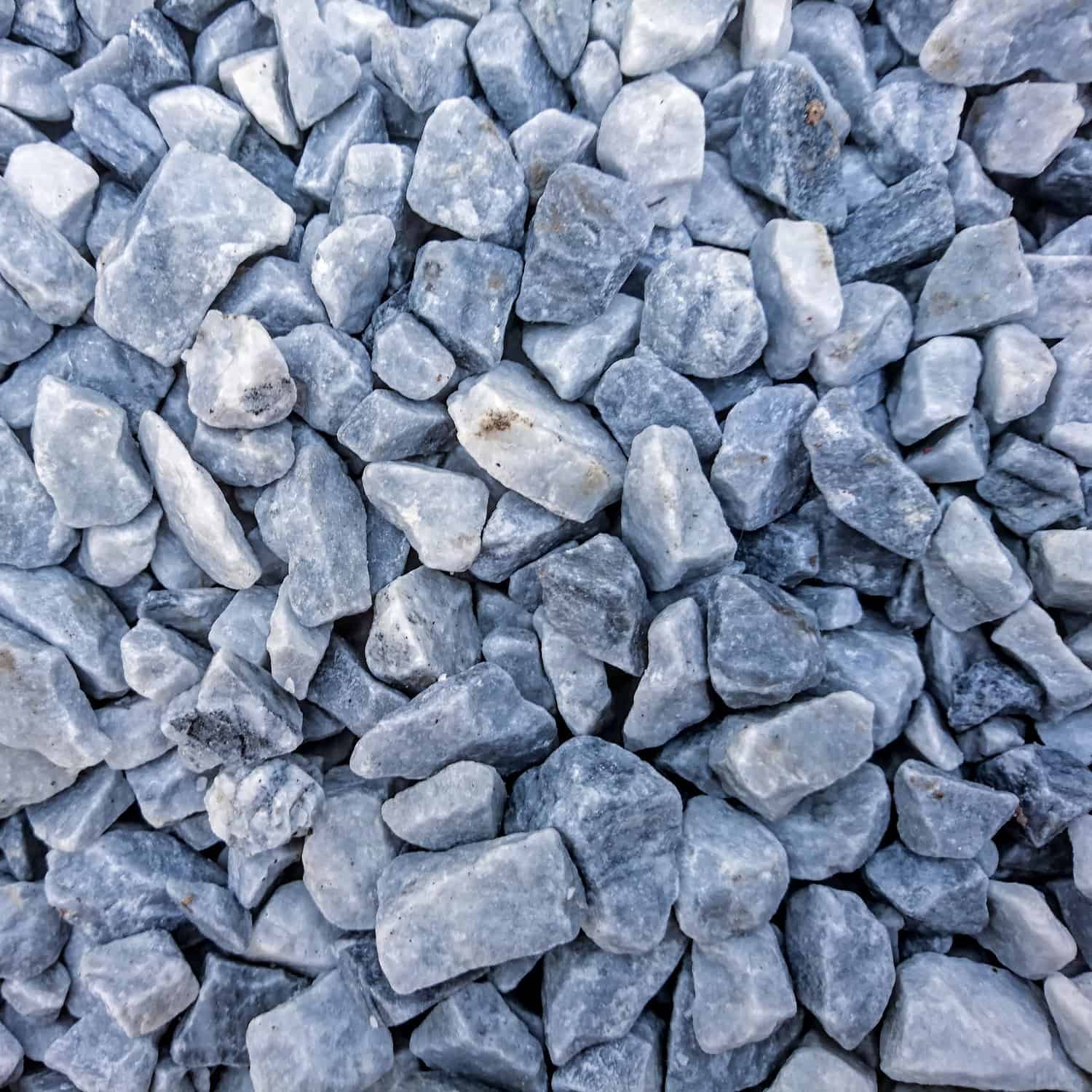 A close-up image showcases a loose pile of Blue Ice Chippings 14-20mm, featuring small, irregular gray and white stones that create a beautiful mottled pattern.