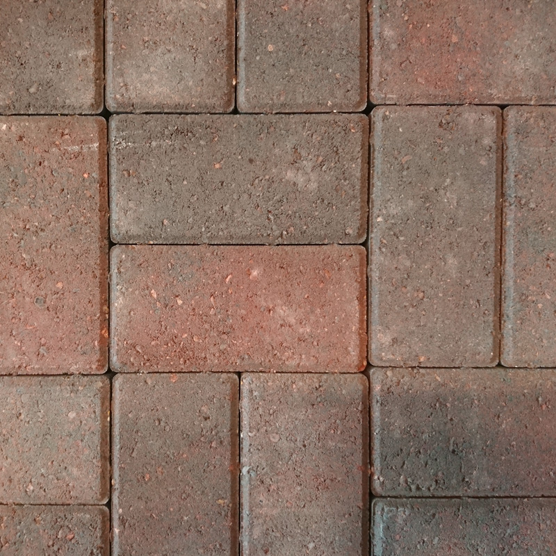 Close-up of a pattern formed by Breedon 50mm Drive Burnt Ochre rectangular stone pavers. Featuring earthy tones of brown and gray, these textured pavers are arranged in a uniform grid creating a neat design that enhances their Burnt Ochre hues.