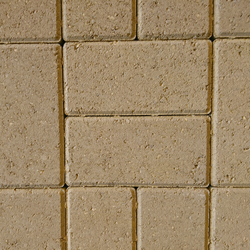 A close-up of a beige brick wall with a rough texture, resembling the classic Breedon style. The Breedon 50mm Drive Buff bricks are rectangular, evenly arranged in a staggered pattern with precise 50mm gaps between them.