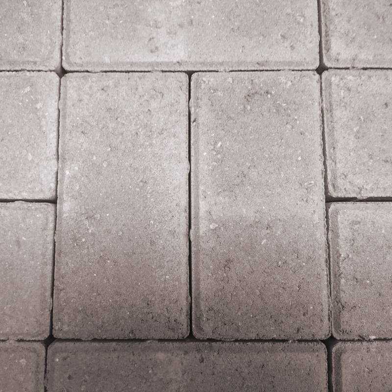 Close-up of Breedon 50mm Drive Natural tiles in a grid pattern. These square stone paving tiles feature a slightly rough texture with natural stone variations and visible wear, offering an earthy and rugged appearance.