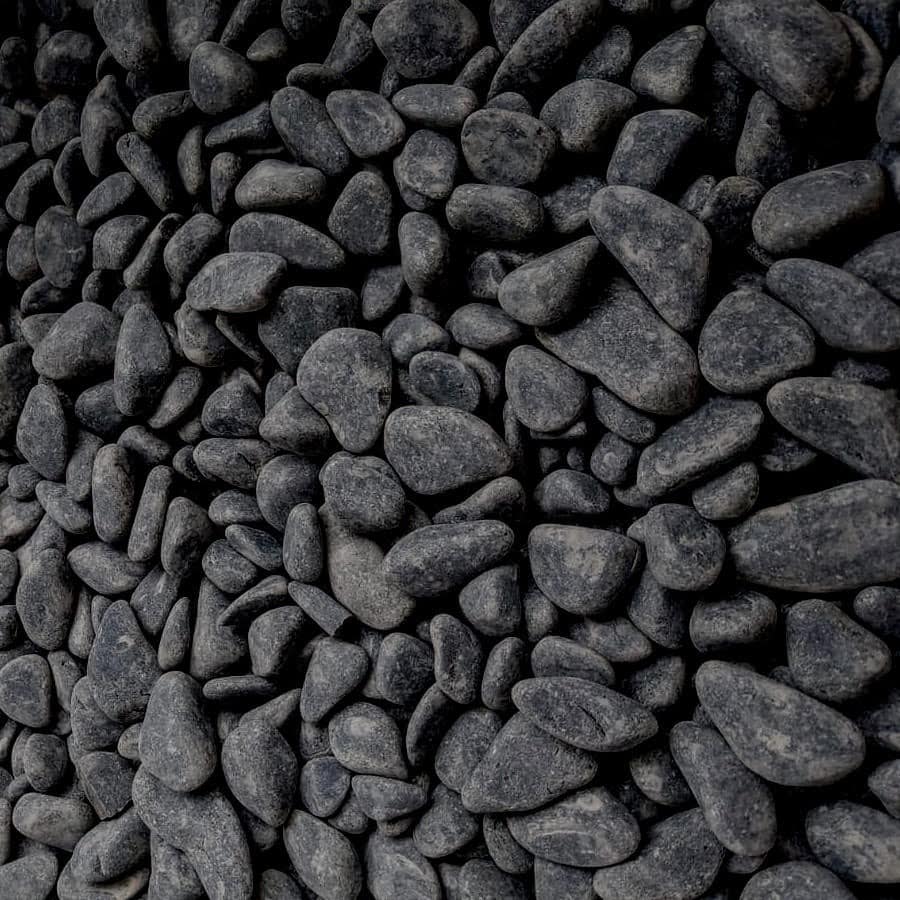 The Ebony Black Cobbles 15-40mm Bagged offer smooth, ebony stones ranging from 15-40mm that create a uniform, textured surface. Slight size and shape variations enhance their consistent dark gray hue and luster.