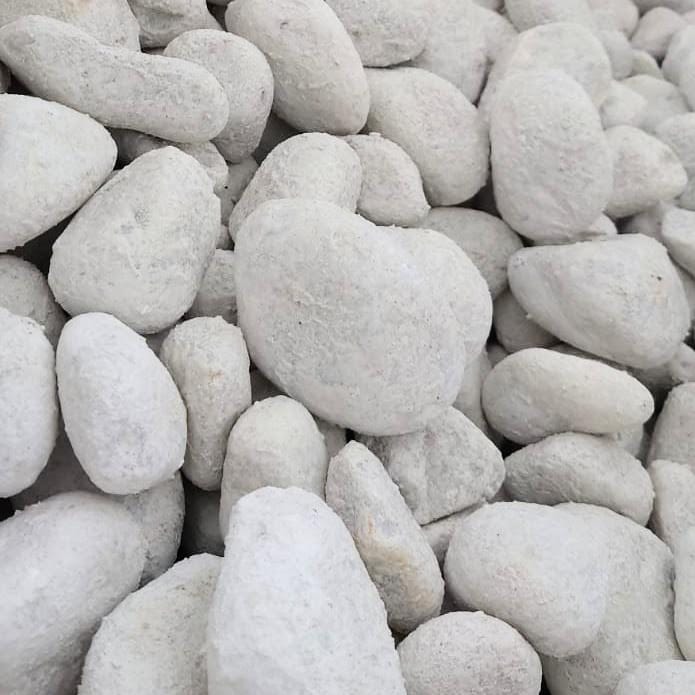 A close-up of Snow White Cobbles 40-90mm - Bagged shows their smooth, chalky surfaces. These stones are tightly packed, filling the frame with pristine allure.