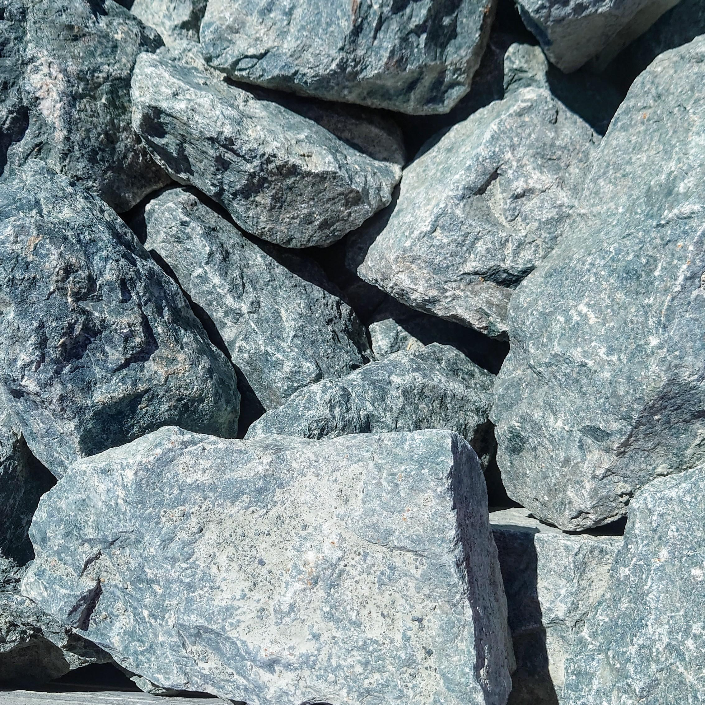 A close-up of 300-400mm Blue Slate Rockery rocks, showcasing their textured, large, and rough blue surfaces under bright sunlight for a striking display.