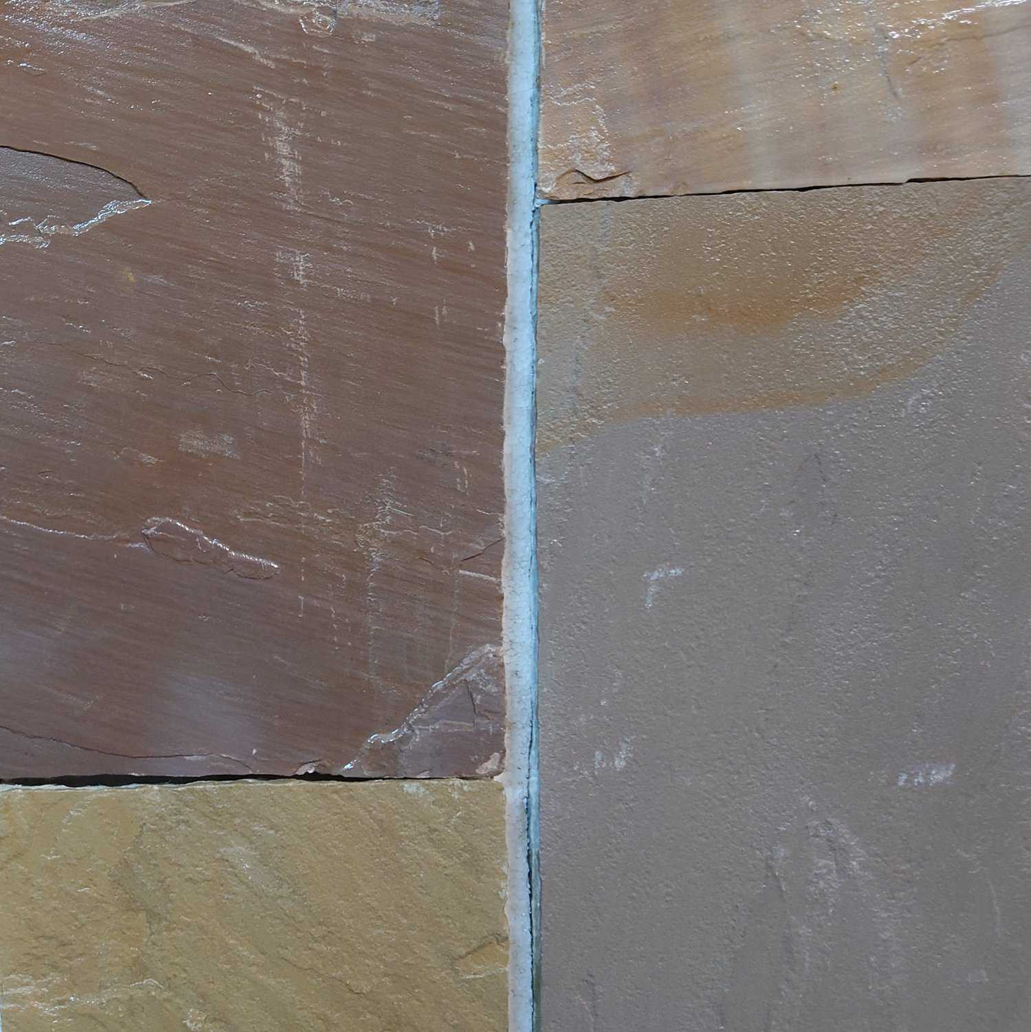 Close-up of a wall featuring two adjacent tiles: the left one is Strata 22mm Calibrated Sandstone RIPPON BUFF with brown horizontal strata, while the right tile is a smooth gray. A thin line of grout subtly separates them.