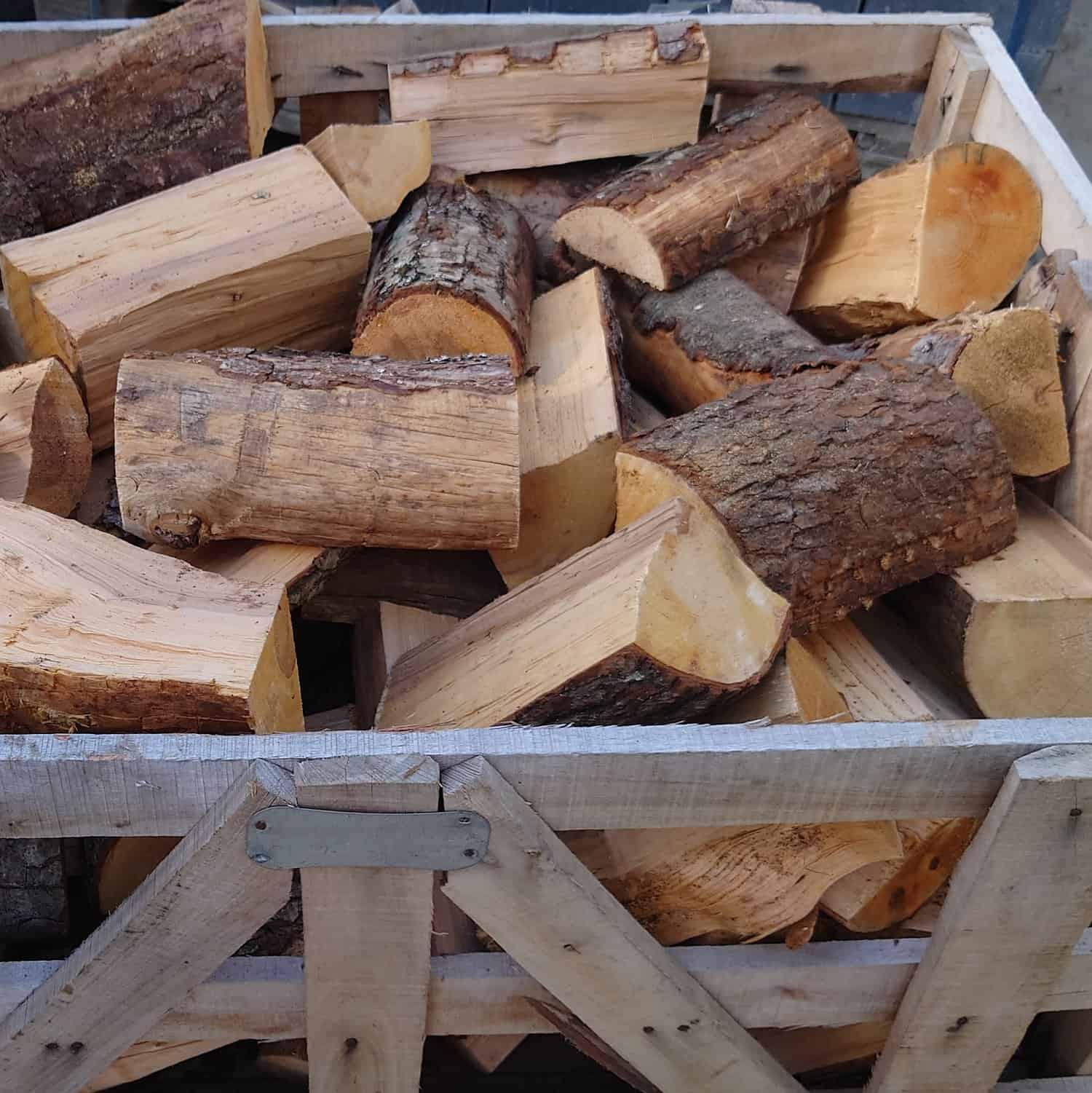 The Kiln Dry Hard Wood Logs 0.31 Cu mtr Crate features a mix of bark-covered and smooth, split surfaces, boasting a sturdy, rustic appearance and showcasing the wood's natural textures.