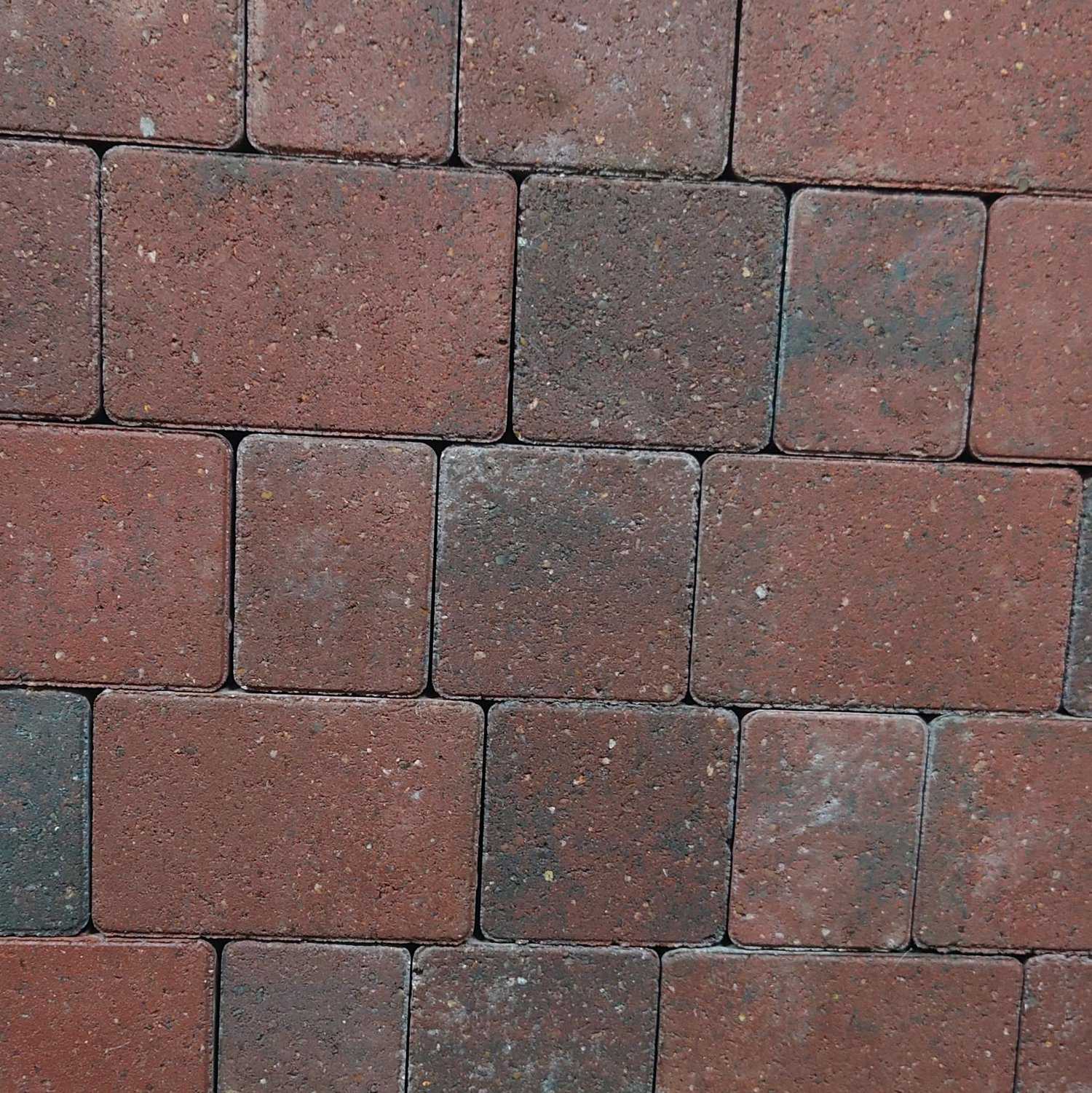 A close-up of Breedon 50mm Suffolk Smooth Brindle Setts arranged in a staggered pattern, featuring alternating red and brown tones. The texture is rough with small white spots, capturing Breedon's rugged charm.