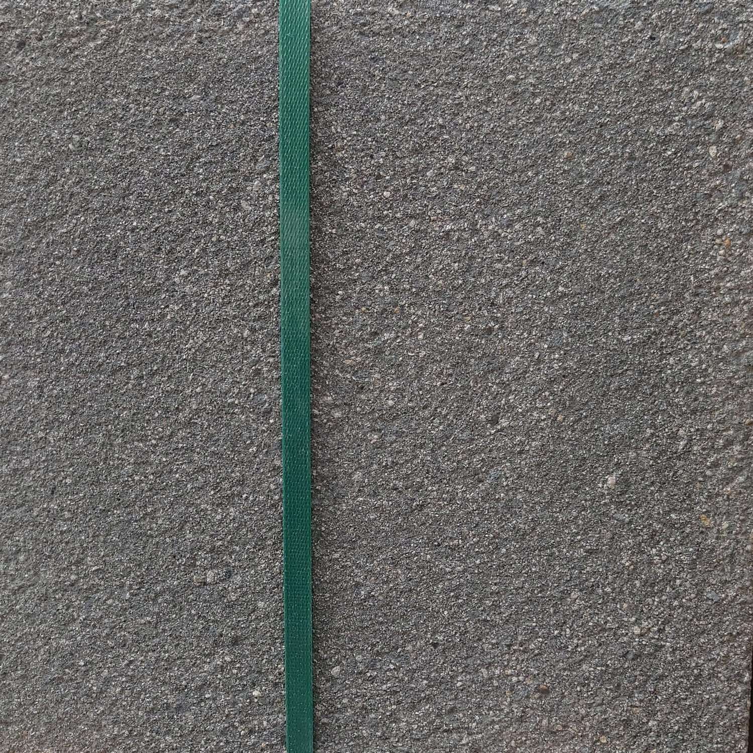 Close-up of a textured, charcoal gray concrete surface featuring a thin green vertical stripe down the middle. The rough, granular appearance highlights the coarse texture reminiscent of Oakdale Centurion Textured 450 x 450 Charcoal finish.